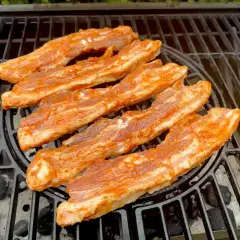 Paski boczku w aromatycznej marynacie do boczku pieką się na grillu.