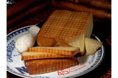 Wędzony ser na talerzu z napisem "Camembert". Obok kawałki sera i biały ser. Idealny do solanki do sera do wędzenia.