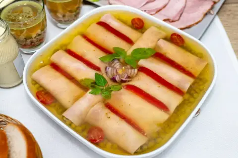 Szynka w galarecie z groszkiem, papryką i pomidorkami. Obok majonez, pieczywo i plastry wędliny.