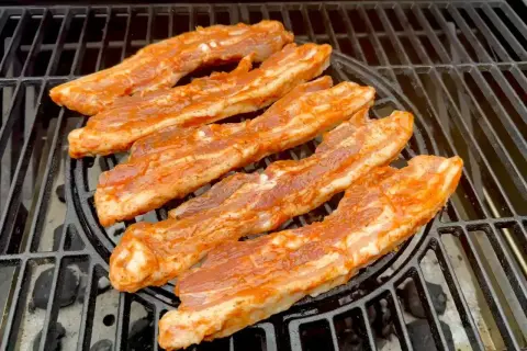 Paski boczku w aromatycznej marynacie do boczku pieką się na grillu.