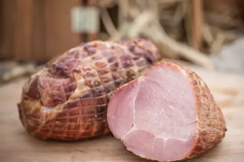 Wędzonka po peklowaniu na sucho próżniowo. Jedna sztuka przekrojona, ukazująca soczyste, różowe mięso.