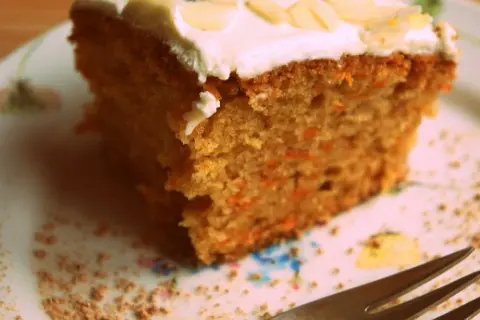 Wilgotne ciasto marchewkowe z puszystą polewą z mascarpone, posypane płatkami migdałów. Idealne na deser.