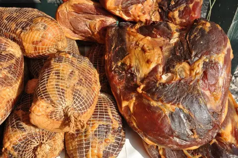 Gotowe do wędzenia mięso: wędzonki w siatkach i duże kawałki wędzonego mięsa. Idealne, by dowiedzieć się, jak przygotować mięso do wędzenia.