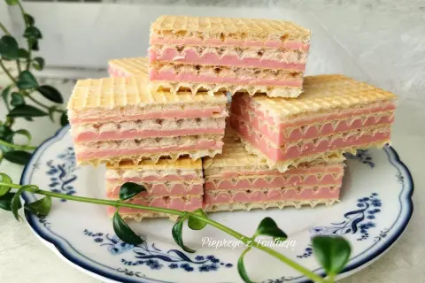 Słodkie wafle z mlekiem w proszku, przełożone różowym kremem, ułożone na talerzyku z niebieskimi wzorami.