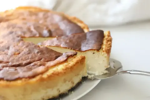 Pyszny sernik z wiaderka z lekko przypieczoną skórką, kroimy pierwszy kawałek.