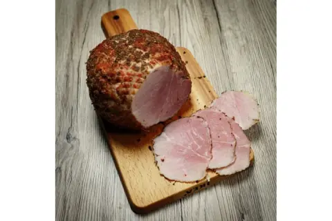 Wędzonka na desce, pokrojona w plastry. Idealna temperatura mięsa w środku podczas wędzenia to klucz do sukcesu.