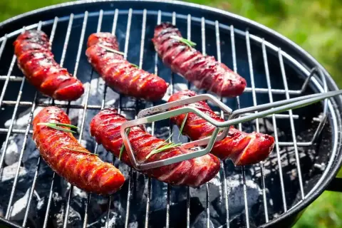 A pyszna kiełbasa na grila, rumiana i soczysta, z gałązkami rozmarynu, pieczona na węglu.