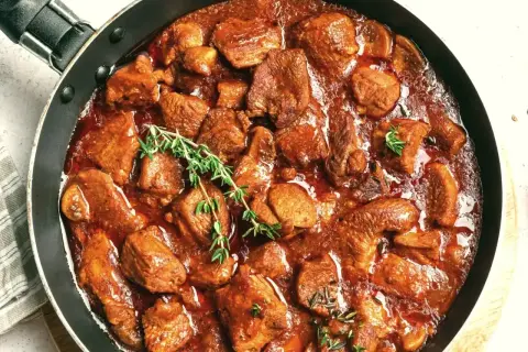 Gulasz wołowy przepis: aromatyczne, duszony kawałki wołowiny w gęstym, czerwonym sosie, udekorowane gałązkami tymianku.