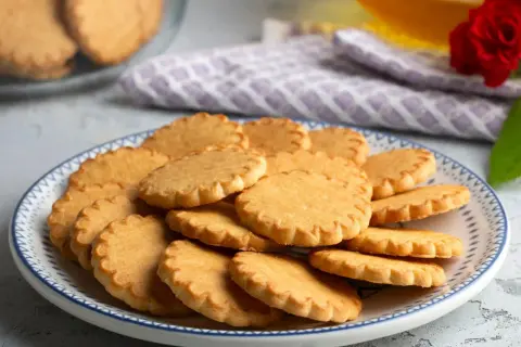 Stos pysznych, szybkich kruchych ciasteczek na talerzu z niebieskim wzorem. Idealne na popołudniową herbatę.