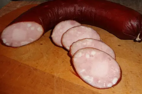 Kiełbasa lisiecka, pokrojona w plastry, na desce. Idealna do przygotowania według tradycyjnego kiełbasa lisiecka przepis.