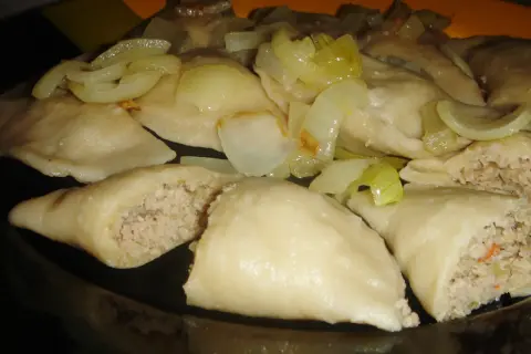 Pyszne pierogi z mięsem i kapustą, polane podsmażoną cebulką, kuszą swoim domowym wyglądem.