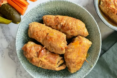 Roladki schabowe pieczone w naczyniu, apetyczne i soczyste, podane z ogórkami i marchewką.