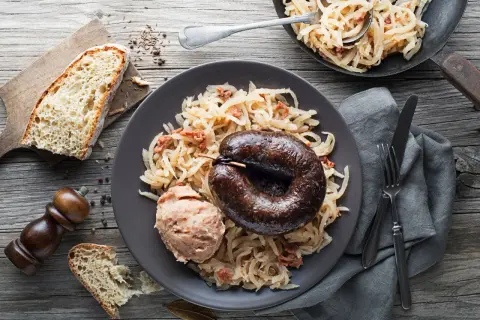 Kaszanka z grilla podana z kapustą kiszoną i chlebem. Pyszne danie, które rozgrzewa.