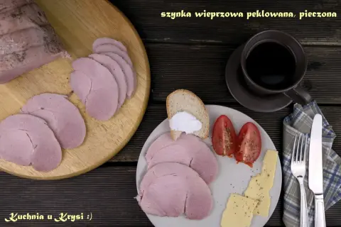 Pyszna, pieczona szynka wieprzowa, pokrojona w plastry, podana z pieczywem, pomidorami i serem. Idealna na śniadanie.