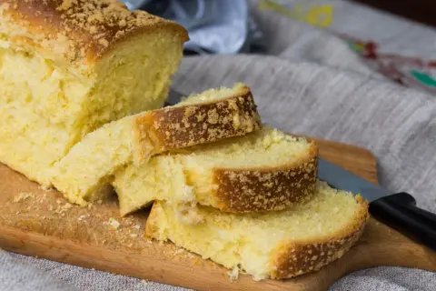 Puszyste ciasto drożdżowe dla leniwych, posypane kruszonką, pokrojone na kromki na desce.