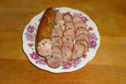 Kiełbasa drwala przepis: pokrojona w plastry, aromatyczna kiełbasa na talerzu z kwiatowym wzorem. Idealna na grilla lub jako dodatek do dania.