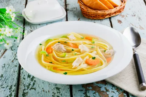 Pyszny, domowy rosół z makaronem do rosołu, kawałkami kurczaka i warzywami. Idealny na chłodne dni.