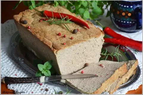 Pyszny pasztet mieszany drobiowo-wieprzowy, udekorowany papryczką chili i ziołami, gotowy do podania na kromce chleba.