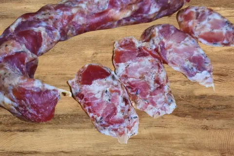 Kiełbasa dojrzewająca, pokrojona w plastry, prezentuje swoje aromatyczne wnętrze. Idealna do domowego wyrobu, gdy szukasz sprawdzonego przepisu.
