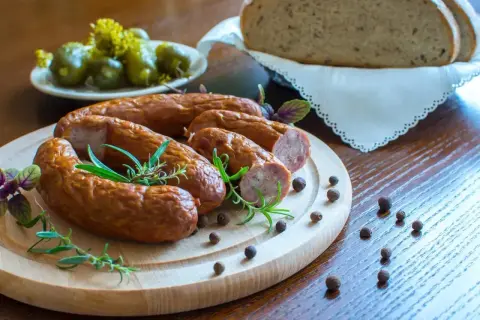 Smaczna kiełbasa na desce z rozmarynem i pieprzem. Zastanawiasz się, ile metrów jelit na 10 kg kiełbasy?