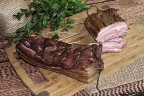 Dwa kawałki wędzonego boczku na desce. Zastanawiasz się, czym natrzeć boczek do wędzenia? Ten wygląda apetycznie!