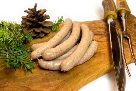 Kiełbasa z dzika na desce, z gałązkami iglaków i szyszką. Idealne jakie przyprawy do kiełbasy z dzika?