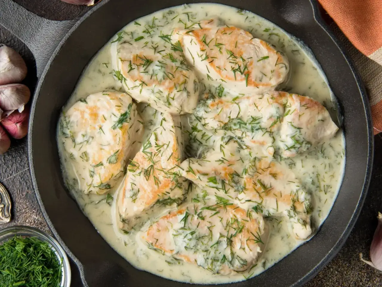 Pyszna potrawka z kurczaka w kremowym sosie z koperkiem, podana w żeliwnej patelni. Aromatyczny dodatek czosnku i świeżego koperku.