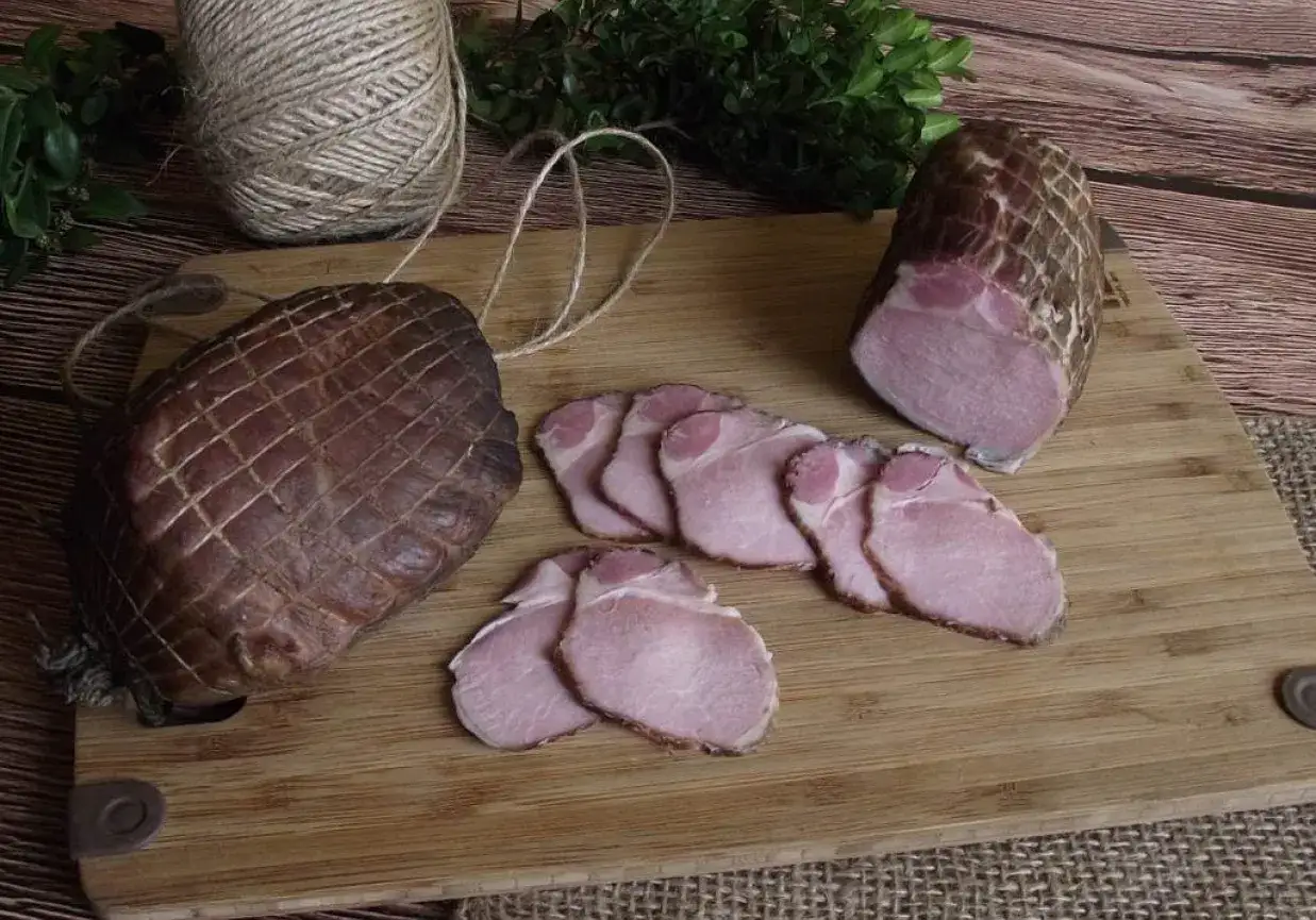 Wędzony schab na desce, obok plasterki. Zastanawiasz się, jak długo wędzić schab, by był idealny?